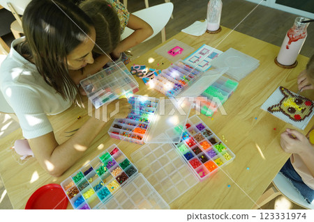 Teacher in workshop teched two girls how to assemble a thermo mosaic  123331974