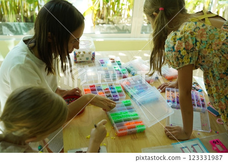 Teacher in workshop teched two girls how to assemble a thermo mosaic  123331987