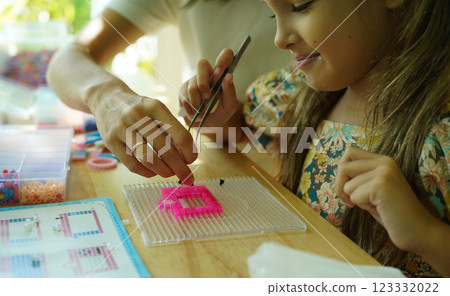 Teacher in workshop teched two girls how to assemble a thermo mosaic  123332022