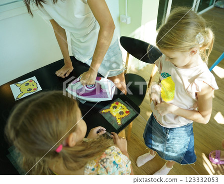 Teacher in workshop teched two girls how to assemble a thermo mosaic  123332053