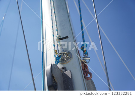 Tall sturdy mast of a sailboat stands out vividly against the bright blue sky. Tall sturdy mast of a sailboat stands out vividly against the bright blue sky. 123332291