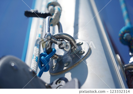 Tall sturdy mast of a sailboat stands out vividly against the bright blue sky. 123332314