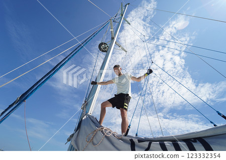 Male captain stands proudly on a sailboat enjoying the moment 123332354