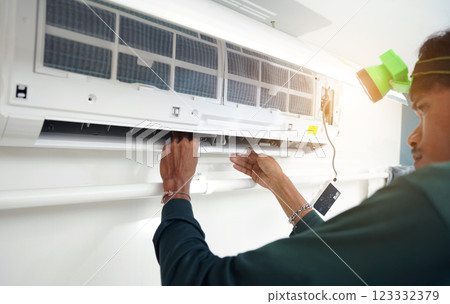 The worker cleans and repairs the air conditioner to ensure it operates properly 123332379