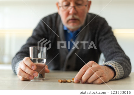 Middle aged senior man holding medical pill and glass of water. Mature old senior grandfather taking medication cure pills vitamin. Age prescription medicine healthcare therapy concept 123333016