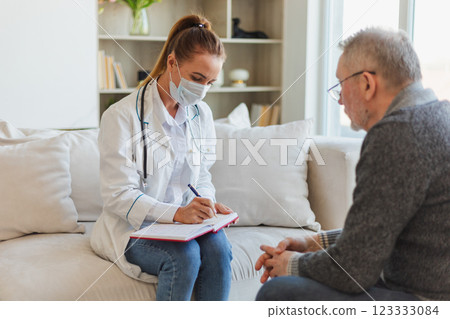 Female doctor examining older senior man in doctor office or at home. Old man patient and doctor have consultation in hospital room. Medicine healthcare medical checkup. Visit to doctor 123333084