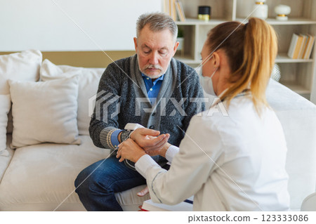 Female doctor senior man taking his blood pressure in doctor office or at home. Old man patient and doctor have consultation in hospital room. Medicine healthcare medical checkup. Visit to doctor Female doctor senior man taking his blood pressure in doctor office or at home. Old man patient and doctor have consultation in hospital room. Medicine healthcare medical checkup. Visit to doctor 123333086