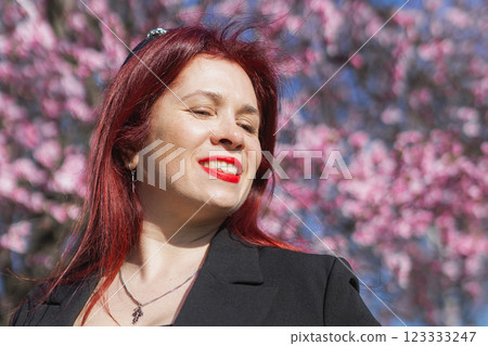 Woman with cherry flowers surrounded by blossoming trees copy space. Beauty and seasonal change and spring bloom season concept. 123333247
