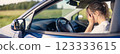 Young woman sitting behind the wheel and covering her face by hands. 123333615
