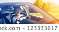 Young woman sitting behind the wheel and driving a car on a sunny day. 123333617