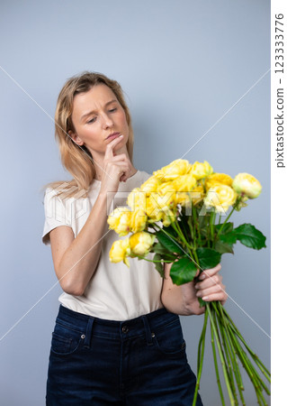 on light gray background a young blonde girl with a large yellow peony roses women's holiday March 8 emotions of discontent and confusion flowers for separation extended finger to mouth on light gray background a young blonde girl with a large yellow peony roses women's holiday March 8 emotions of discontent and confusion flowers for separation extended finger to mouth 123333776