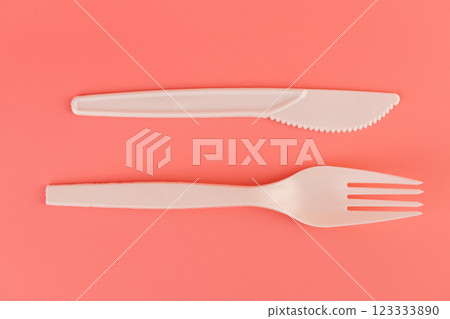 top shot close-up on soft pink background pair of plastic white knives and forks disposable tableware eco technology reusable care for planet picnic set 123333890