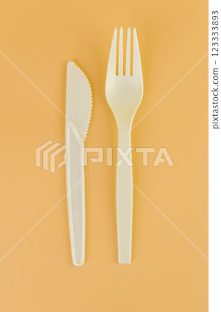 top shot close-up on soft yellow background pair of plastic white knives and forks disposable tableware eco technology reusable care for planet picnic set top shot close-up on soft yellow background pair of plastic white knives and forks disposable tableware eco technology reusable care for planet picnic set 123333893