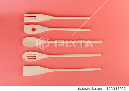 top shot close-up on soft pink background lie new kitchen light wooden utensils of different shapes spatulas for tephlon coating natural wood handmade different types of use 123333922