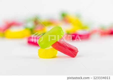 closeup on white background lie three caramel candies green pink yellow on the background of candies a lot of sugar development of diabetes and caresses sweets for children closeup on white background lie three caramel candies green pink yellow on the background of candies a lot of sugar development of diabetes and caresses sweets for children 123334011