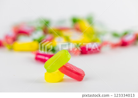 on white background lie three caramel candies green pink yellow on the background of candies a lot of sugar development of diabetes and caresses sweets for children 123334013