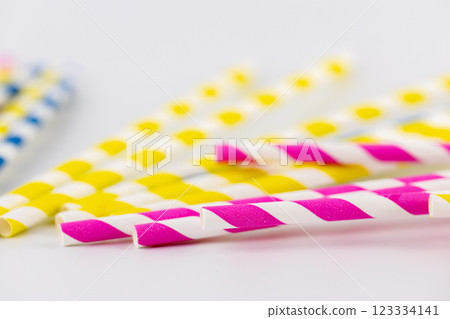 closeup on white background there are many paper striped colored tubes for cocktails and different drinks pink yellow and blue striped tubes spring mood 123334141