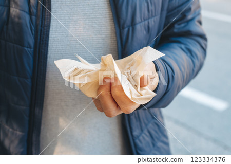 man about to use a recycled paper tissue outdoors 123334376