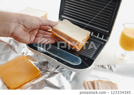 man about to toast a sandwich on a sandwich toaster 123334385