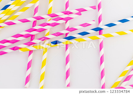 top shot on white background there are many paper striped colored tubes for cocktails and different drinks pink yellow and blue striped tubes spring mood 123334784