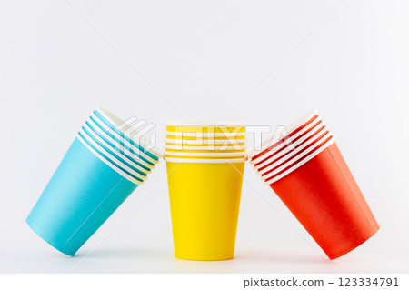 white background a stack of paper cups for coffee and tea painted in red and blue rest on yellow disposable tableware for trips vacations and picnics eco cups waterproof house of cards 123334791