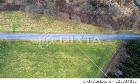 Aerial View of an Empty Road that is Surrounded by Beautiful Lush Green Fields and Nature Aerial View of an Empty Road that is Surrounded by Beautiful Lush Green Fields and Nature 123334818