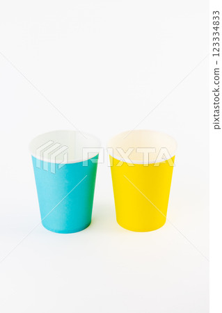 top shot on white background two paper cups for coffee and tea painted in yellow and blue disposable tableware attributes for trips, recreation and picnics eco cups waterproof top shot on white background two paper cups for coffee and tea painted in yellow and blue disposable tableware attributes for trips, recreation and picnics eco cups waterproof 123334833