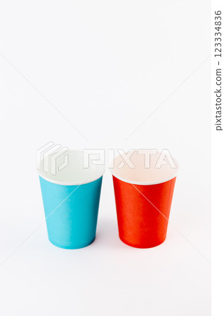 on white background two paper cups for coffee and tea painted in red and blue disposable tableware attributes for trips, recreation and picnics eco cups waterproof on white background two paper cups for coffee and tea painted in red and blue disposable tableware attributes for trips, recreation and picnics eco cups waterproof 123334836