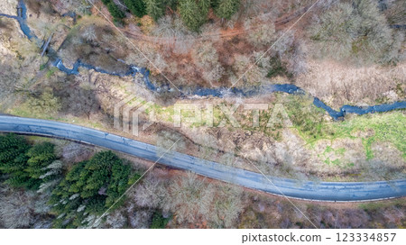 Aerial view of a winding road through a lush forest, showcasing outdoor beauty and adventure Aerial view of a winding road through a lush forest, showcasing outdoor beauty and adventure 123334857