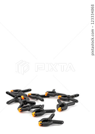 close-up on white background there is a lot of small plastic black clamp with an orange lock a tool in everyday life reliable fixation repair tool 123334868