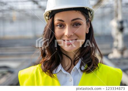 Smiling young female engineer in a hardhat and yellow vest Smiling young female engineer in a hardhat and yellow vest 123334873