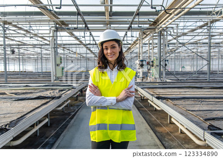 Smiling young female engineer in a hardhat and yellow vest Smiling young female engineer in a hardhat and yellow vest 123334890