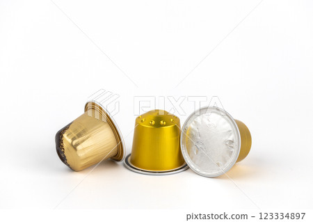 close-up on white background lie three golden capsules for coffee of different strengths modern coffee machines disposable use preservation of tightness 123334897