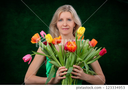 A beautiful adult woman with a bouquet of flowers on a dark background. A beautiful adult woman with a bouquet of flowers on a dark background. 123334953