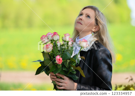 Happy adult blonde woman with a bouquet of roses on a natural background. Happy adult blonde woman with a bouquet of roses on a natural background. 123334957