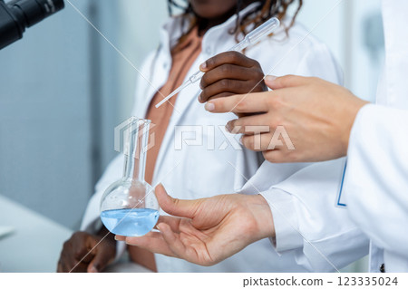 Diverse researchers in laboratory holding reagent tube and analyzing fluid samples 123335024