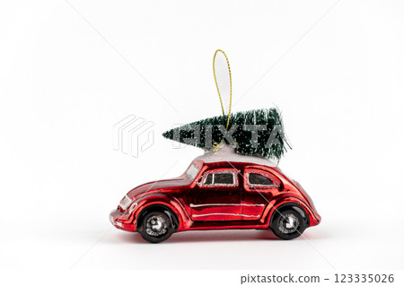 on white background there is a glass enameled Christmas tree toy in the shape of a red retro car that is carrying a Christmas tree, a modern decor toy with sparkles white on white background there is a glass enameled Christmas tree toy in the shape of a red retro car that is carrying a Christmas tree, a modern decor toy with sparkles white 123335026