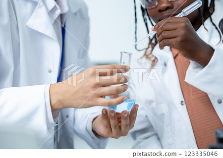 Diverse medical woman and man in laboratory holding transparent flask with chemical solution Diverse medical woman and man in laboratory holding transparent flask with chemical solution 123335046