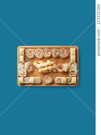top shot on blue background on a light wooden tray lies a set of sushi with rice and seafood sushi in batter in the center fried shrimp in batter professional cuisine top shot on blue background on a light wooden tray lies a set of sushi with rice and seafood sushi in batter in the center fried shrimp in batter professional cuisine 123335160