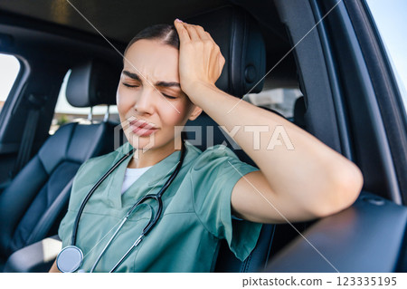 Female nurse sitting in a car and having a headache 123335195