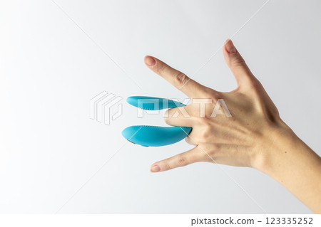 on white background on women's fingers blue vibrator for double penetration pleasure for two waterproof modern device variety for a couple partner replacement on white background on women's fingers blue vibrator for double penetration pleasure for two waterproof modern device variety for a couple partner replacement 123335252