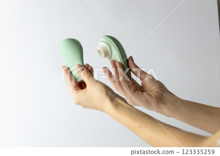 on white background female hands vacuum vibrator and its cover gently mint color device for girls relaxation for adults egg shape magnetic charging water resistance 123335259