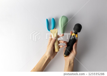 on white background, a woman s hand holds a large black vibrator in the shape of a microphone, lubricant in a tube, a vacuum mint and double blue vibrators lie nearby, various sex toys on white background, a woman s hand holds a large black vibrator in the shape of a microphone, lubricant in a tube, a vacuum mint and double blue vibrators lie nearby, various sex toys 123335286