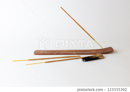 close-up on a white background on a long brown stand with stars for incense sticks placed new beige meditation stick palosanto traditional set close-up on a white background on a long brown stand with stars for incense sticks placed new beige meditation stick palosanto traditional set 123335302