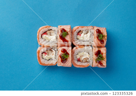 on blue background lies a set of sushi with rice and seafood avocado sushi wrapped in salmon meat red caviar with seaweed professional Japanese cuisine kitchen sushi without shade on blue background lies a set of sushi with rice and seafood avocado sushi wrapped in salmon meat red caviar with seaweed professional Japanese cuisine kitchen sushi without shade 123335326