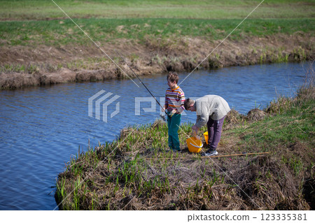 The boys are fishing on a small river. Friends go fishing in the summer. 123335381