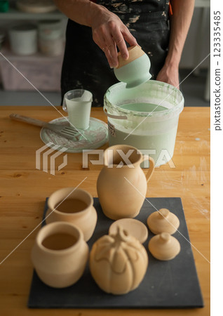 Close-up of a potter's hands glazing a pottery piece. Close-up of a potter's hands glazing a pottery piece. 123335485