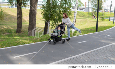 Caucasian woman roller skating with her toddler son in a stroller. Caucasian woman roller skating with her toddler son in a stroller. 123335608