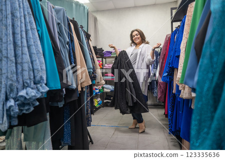 A fat woman chooses clothes in a plus size store.  123335636