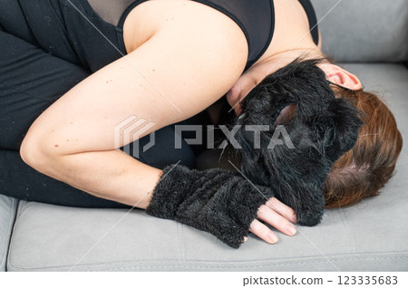 A woman in a cat costume lies on a gray sofa. Quadrober.  123335683